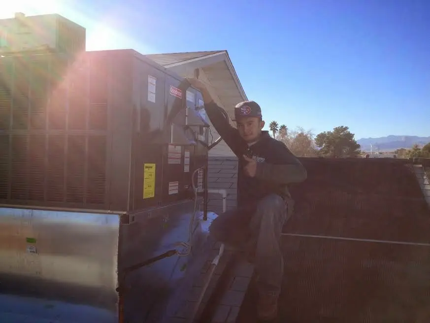 HVAC technician performing Air Duct Repair on a rooftop unit in Olivette